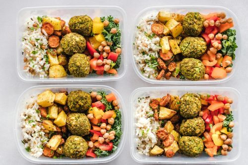 Colorful meal prep containers with falafel, chickpeas, rice, and vegetables for a healthy lifestyle.