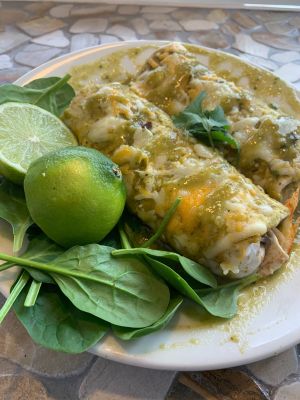 Fresh mixed green salad with cherry tomatoes, walnuts, pomegranates, and a breadstick in a black bowl.